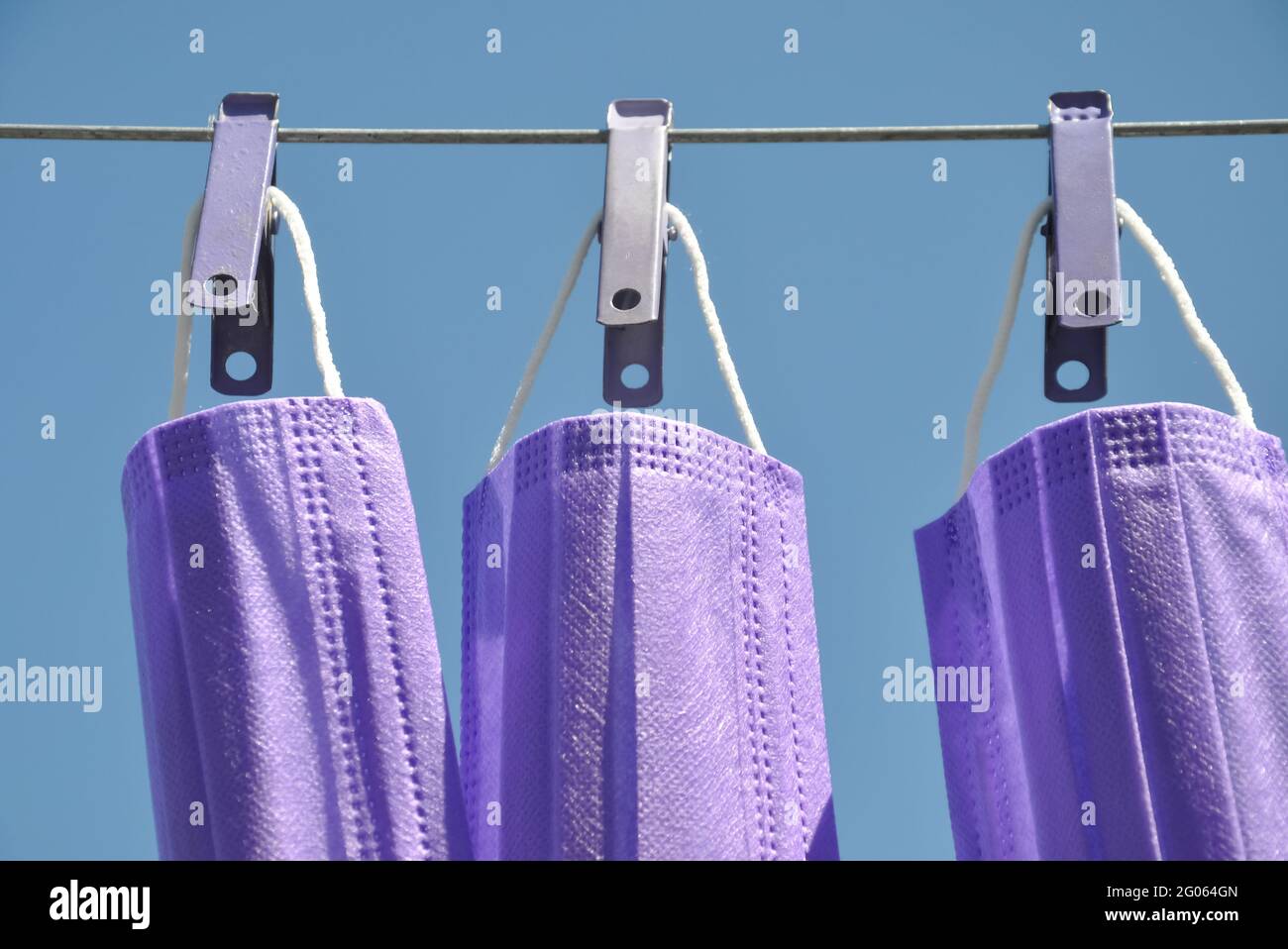 Vista frontale della maschera chirurgica di colore blu appesa al filo della stendibiancheria con stendibiancheria, concetto di protezione dell'ambiente da rifiuti e inquinamento. Foto Stock