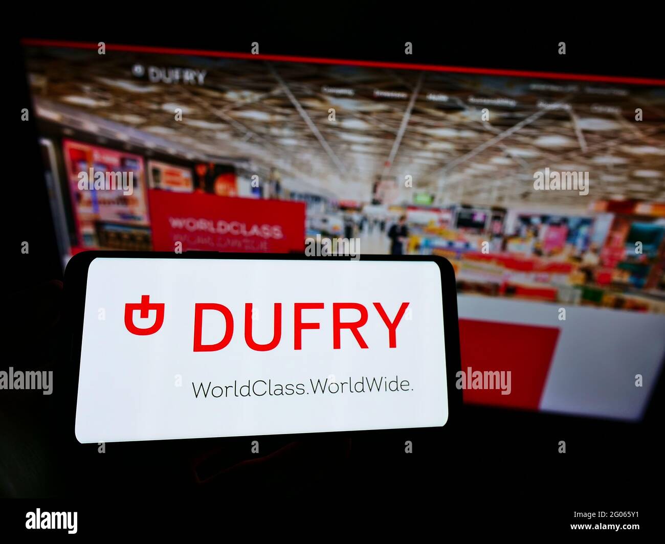 Persona che detiene il cellulare con il logo commerciale della società svizzera al dettaglio Dufry AG sullo schermo davanti alla pagina web. Mettere a fuoco il display del telefono. Foto Stock