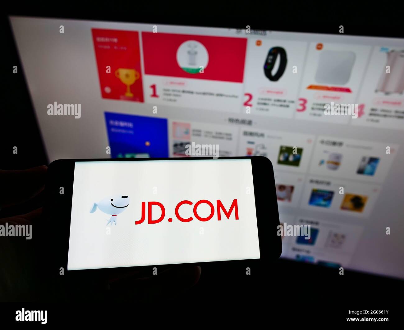 Persona che tiene il telefono mobile con il logo della società cinese di e-commerce JD.com Inc. Sullo schermo di fronte al negozio online. Mettere a fuoco il display del telefono. Foto Stock