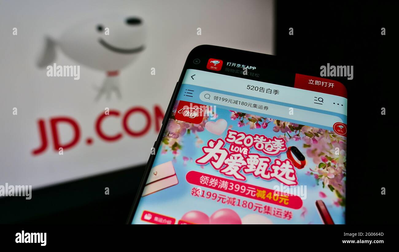 Cellulare con pagina web con negozio online della società cinese di e-commerce JD.com Inc. Su schermo davanti al logo. Mettere a fuoco in alto a sinistra del display del telefono. Foto Stock