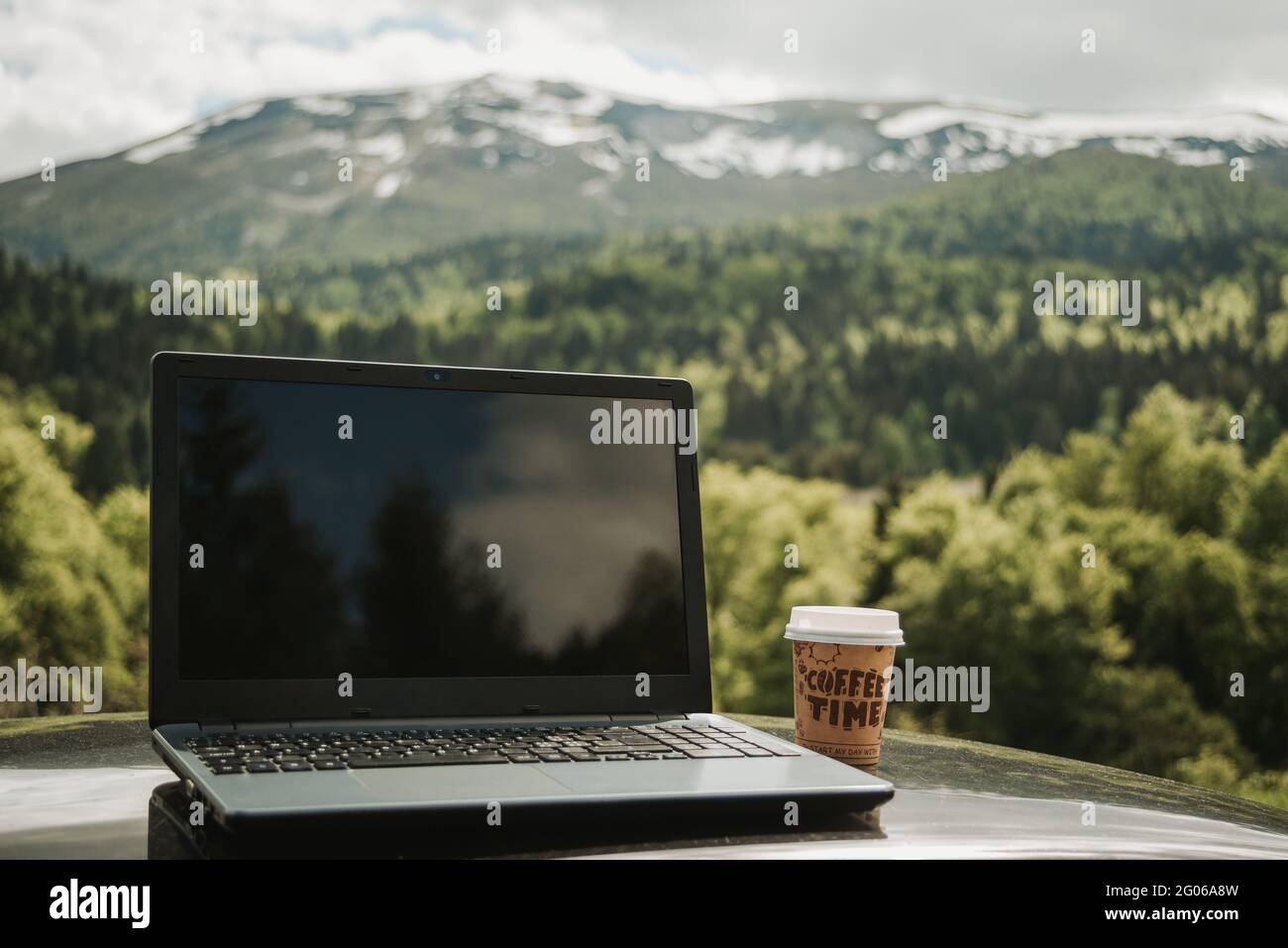 computer portatile all'aperto con caffè, posizione remota nella natura con bella connessione internet in montagna, libertà freelance Foto Stock