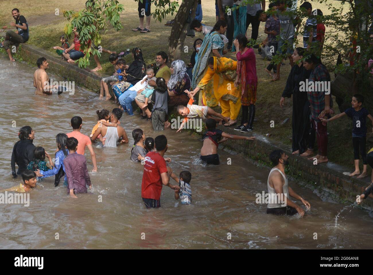Pakistano un gran numero di persone che prendono il bagno all'interno del canale acqua per ...