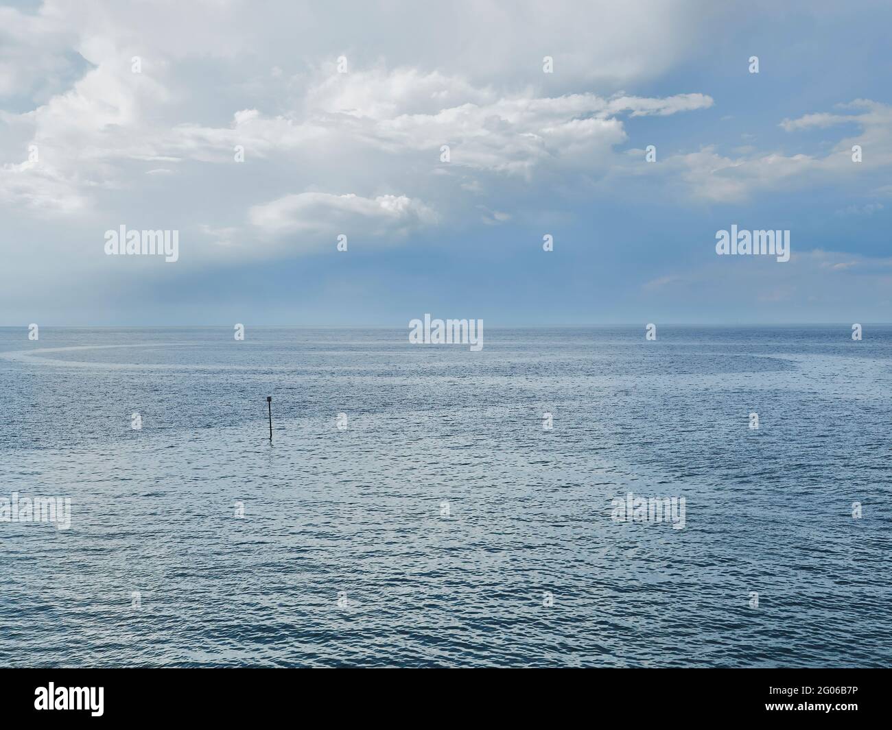 Un ampio e aperto mare che cattura il modello delle correnti d’acqua e i riflessi dell’intricato paesaggio torbido. Una solitaria boa dà scala Foto Stock