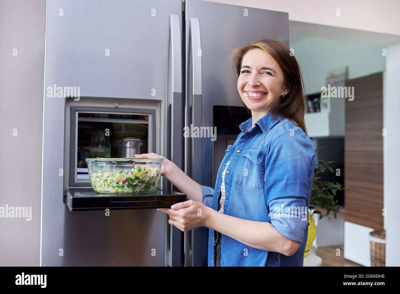 Donna con ciotola di insalata di verdure dal frigorifero. Foto Stock