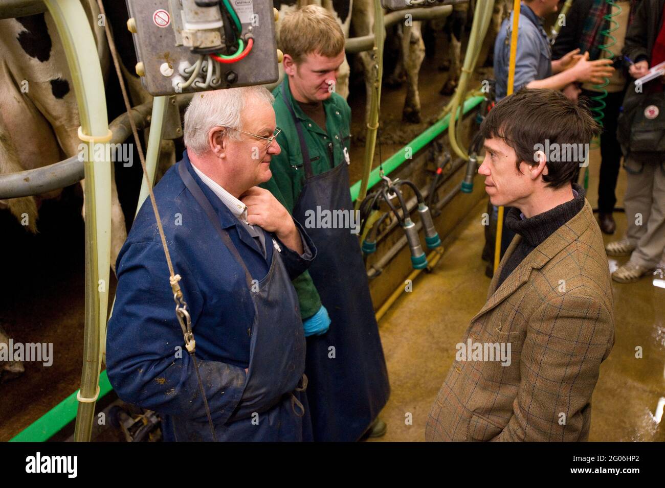 Rory Stewart, candidato parlamentare conservatore per la Penrith e la circoscrizione del confine, parla con gli agricoltori James Gibson (tuta blu) e suo figlio Chris Gibson (tuta verde) durante la mungitura mattutina. Parte della campagna elettorale generale di Rory del 2010. Castlesteads Farm, Plumpton, Cumbria, Regno Unito. 16 Apr 2010 Foto Stock