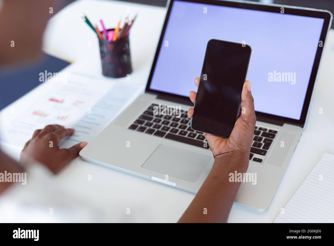 Donna afroamericana che usa un computer portatile e uno smartphone con spazi di copia sugli schermi Foto Stock