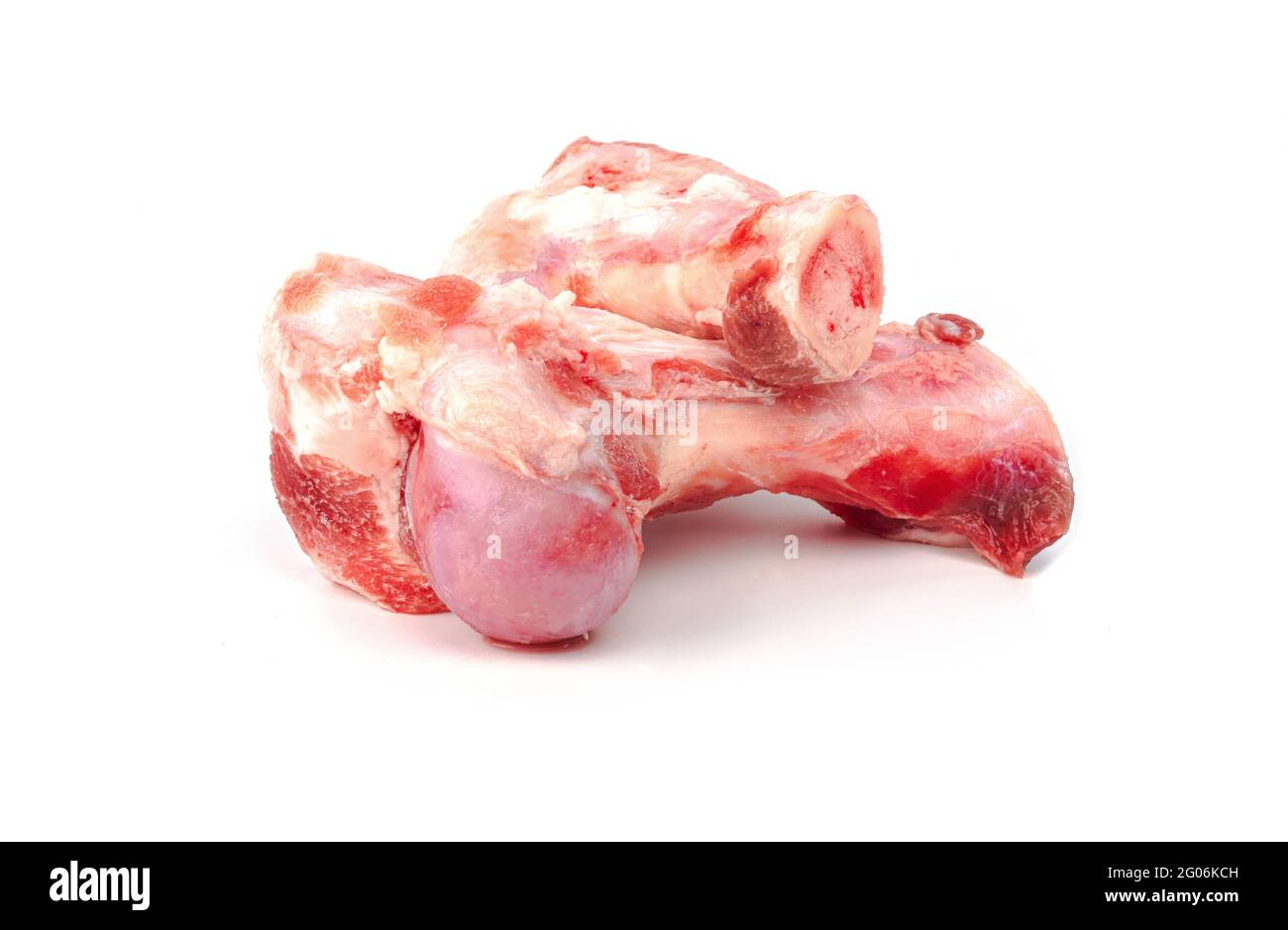 Primo piano ossa fresche di maiale congelate con carne rossa attaccata per la preparazione di brodo di ossa di maiale su sfondo bianco Foto Stock