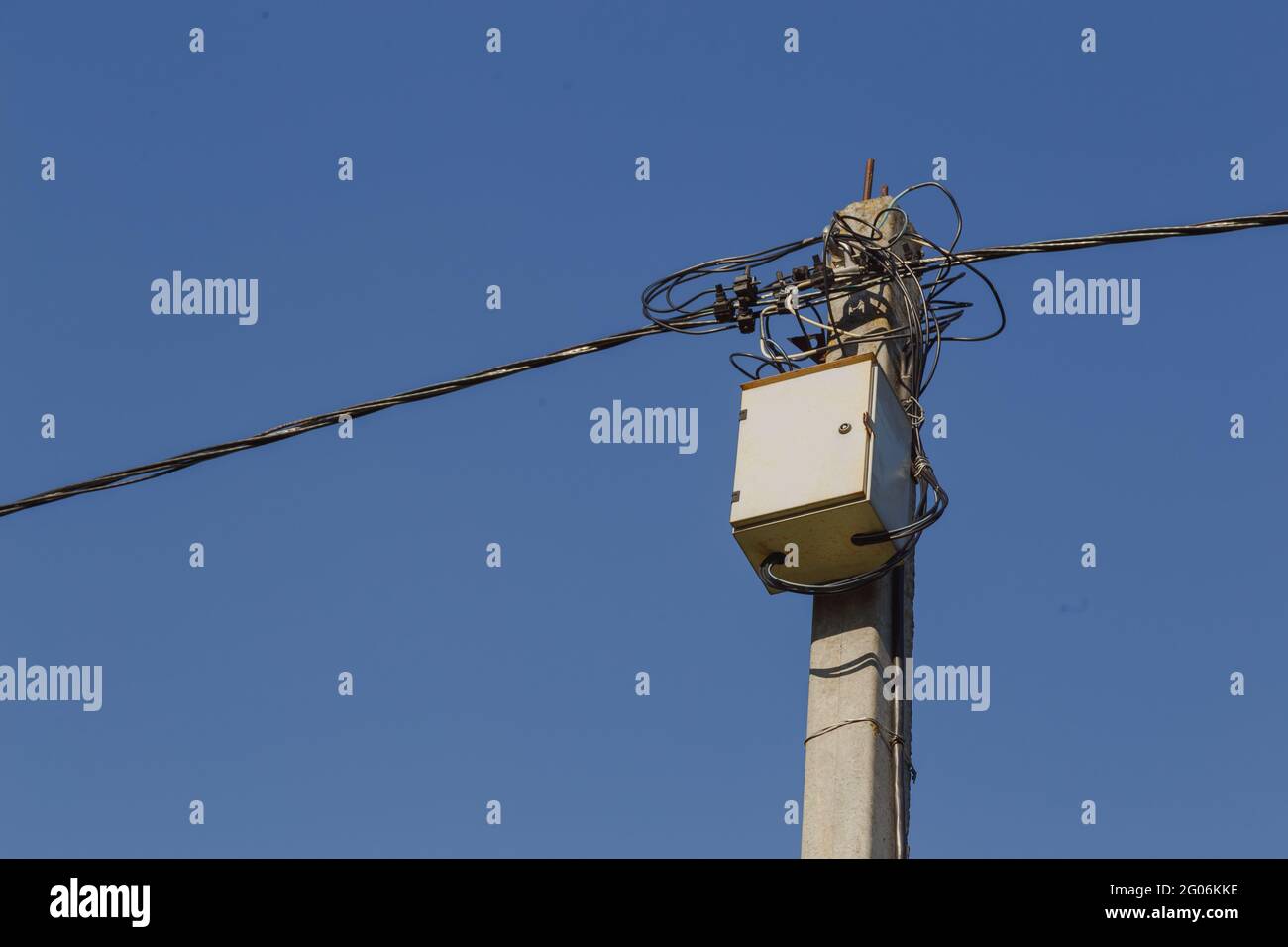 Scatola trasformatore di distribuzione e linea elettrica su palo in cemento Foto Stock