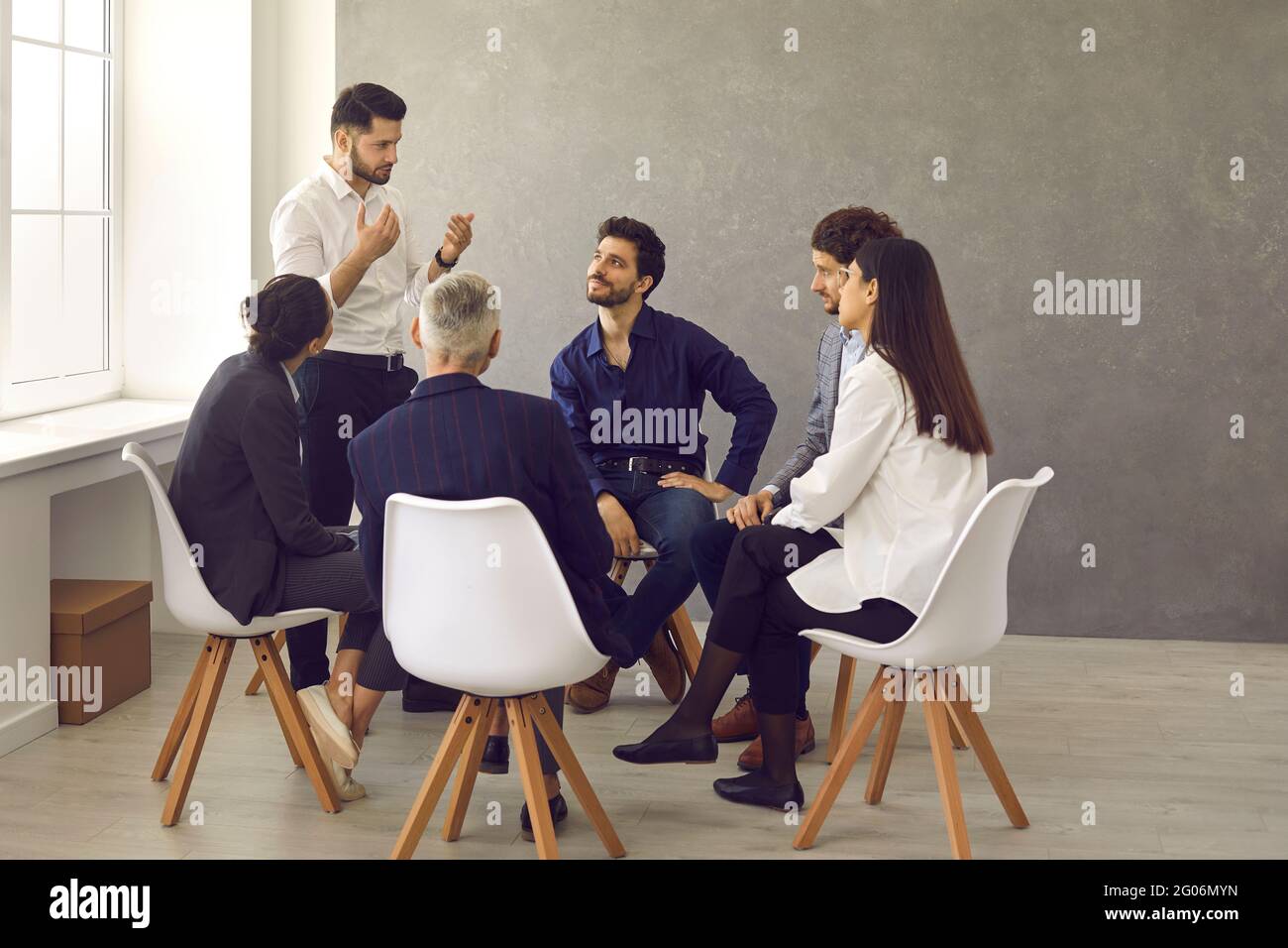 Giovane manager o allenatore di affari che ha una discussione con un gruppo di lavoratori aziendali Foto Stock