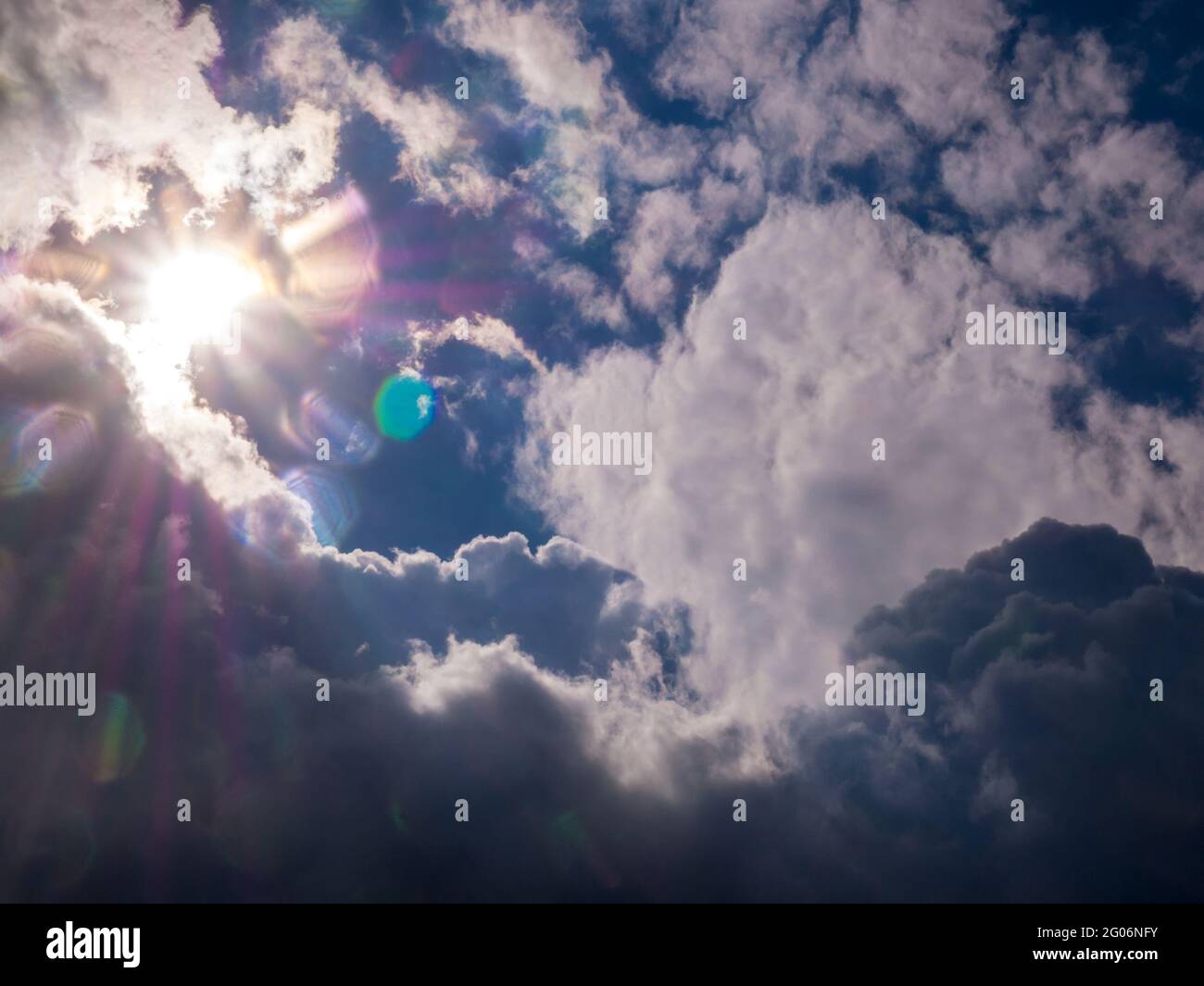 Sole con raggi nel cielo blu e nuvole spesse Foto Stock