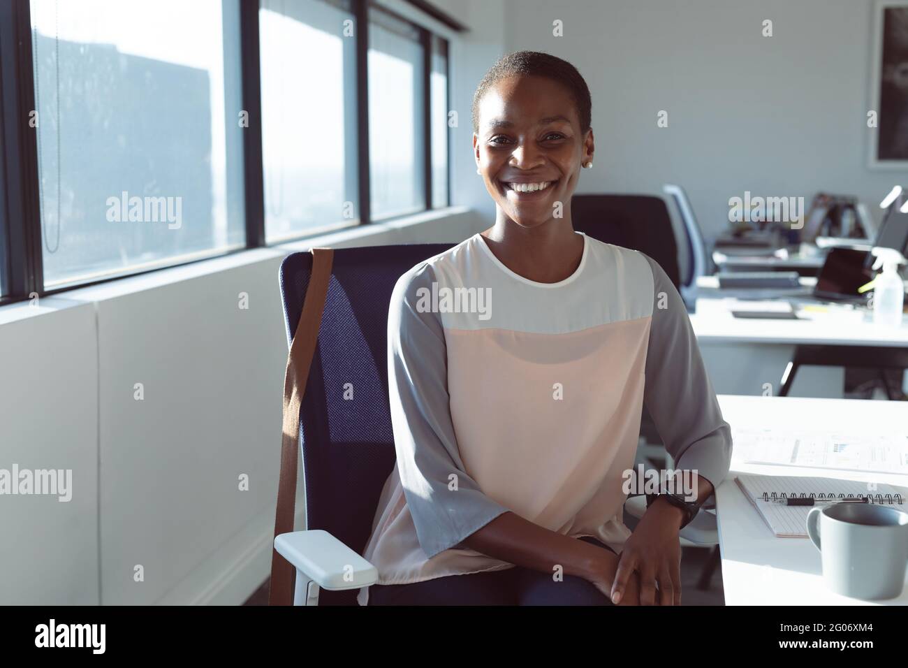 Donna d'affari afroamericana sorridente seduto alla scrivania al lavoro Foto Stock