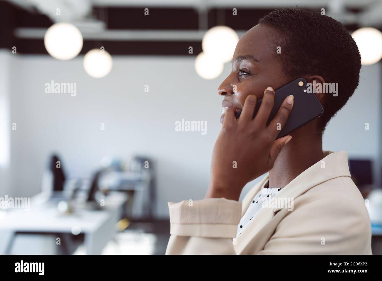 Sorridente donna d'affari afroamericana che usa lo smartphone al lavoro Foto Stock