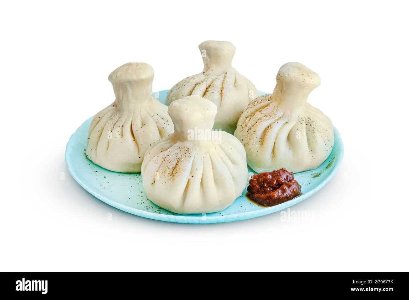 khinkali su un piattino con forte adjika isolato su sfondo bianco Foto Stock