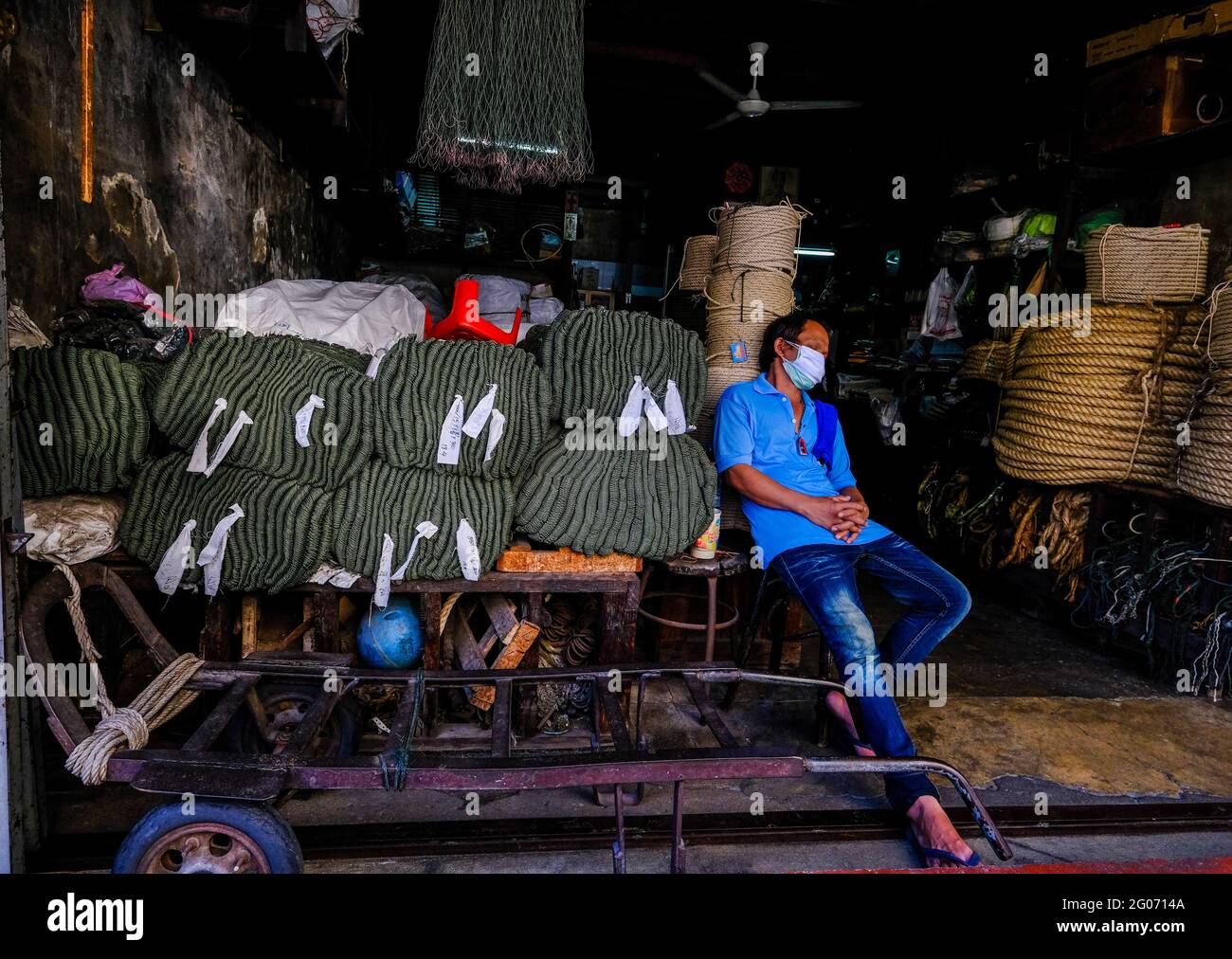 Un lavoratore maschile prende un pisolino pomeridiano davanti ai suoi locali nella zona di Chinatown a Bangkok, in Thailandia. Foto Stock