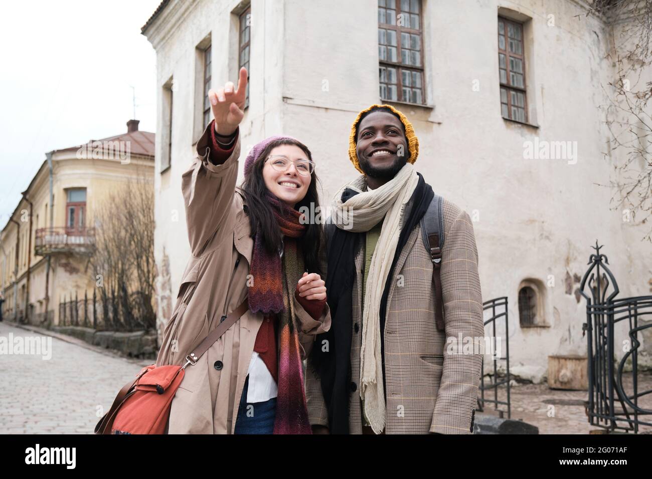 Giovane donna che indica qualcosa mentre si è in piedi con l'uomo in città durante la visita turistica Foto Stock