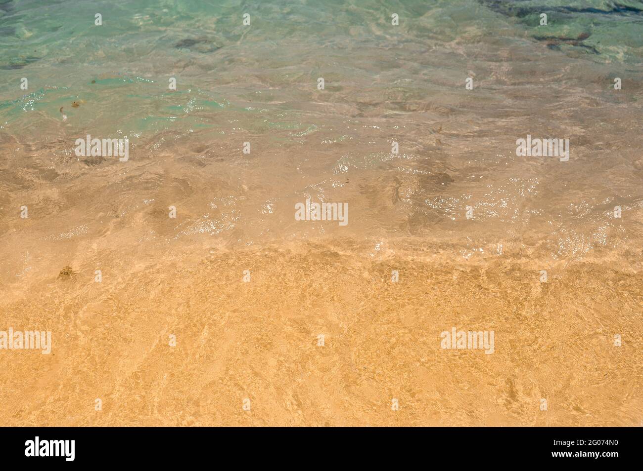 consistenza di acqua che corre onde sulla sabbia sulla spiaggia. Estate spiaggia sfondo. Sabbia e mare e cielo blu. Sabbia dorata con oceano blu Foto Stock