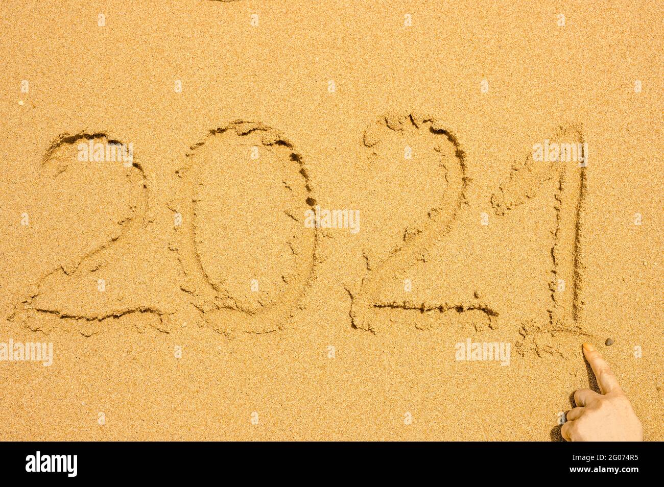 Testo scritto a mano 2021 sulla sabbia bagnata dorata sulla spiaggia. Recupero dopo covid-19 concetto e viaggio di felicità Foto Stock