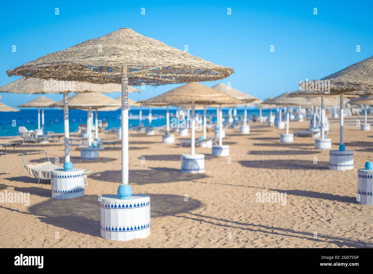 Spiaggia vuota mare sabbia cielo e giorno d'estate. Abstract bokeh estate e sfondo mare. Le persone si rilassano sui lettini sotto un ombrellone in riva al mare. Vacanze, vca Foto Stock