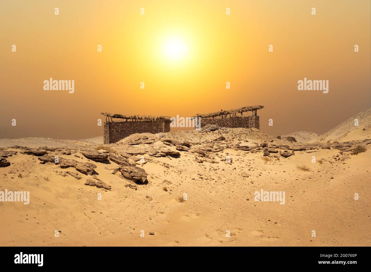 Piccole capanne nel mezzo del deserto con uno sfondo paesaggio incredibile. Rifugio in pietra del deserto sotto il sole bruciante. Tramonto nel deserto Foto Stock