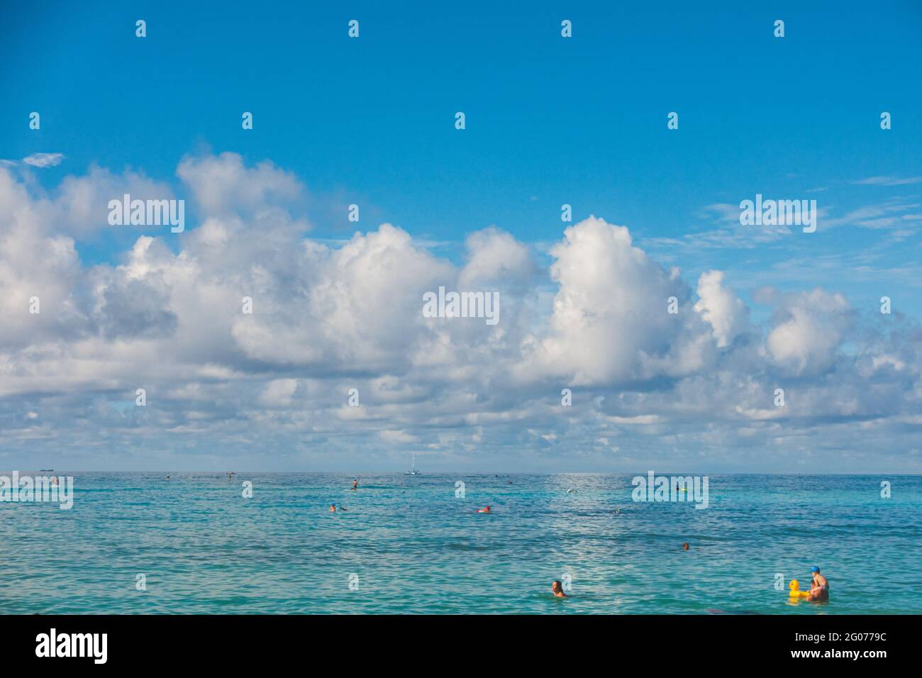 Oahu Hawaii persone godere Waikiki in acque turchesi contro cielo e nuvole Foto Stock