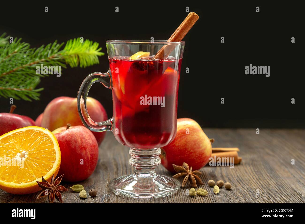 VIN brulé con spezie e frutta su un tavolo di legno su fondo nero. Tradizionale bevanda calda natalizia con vino rosso, mele, arance e cannella Foto Stock