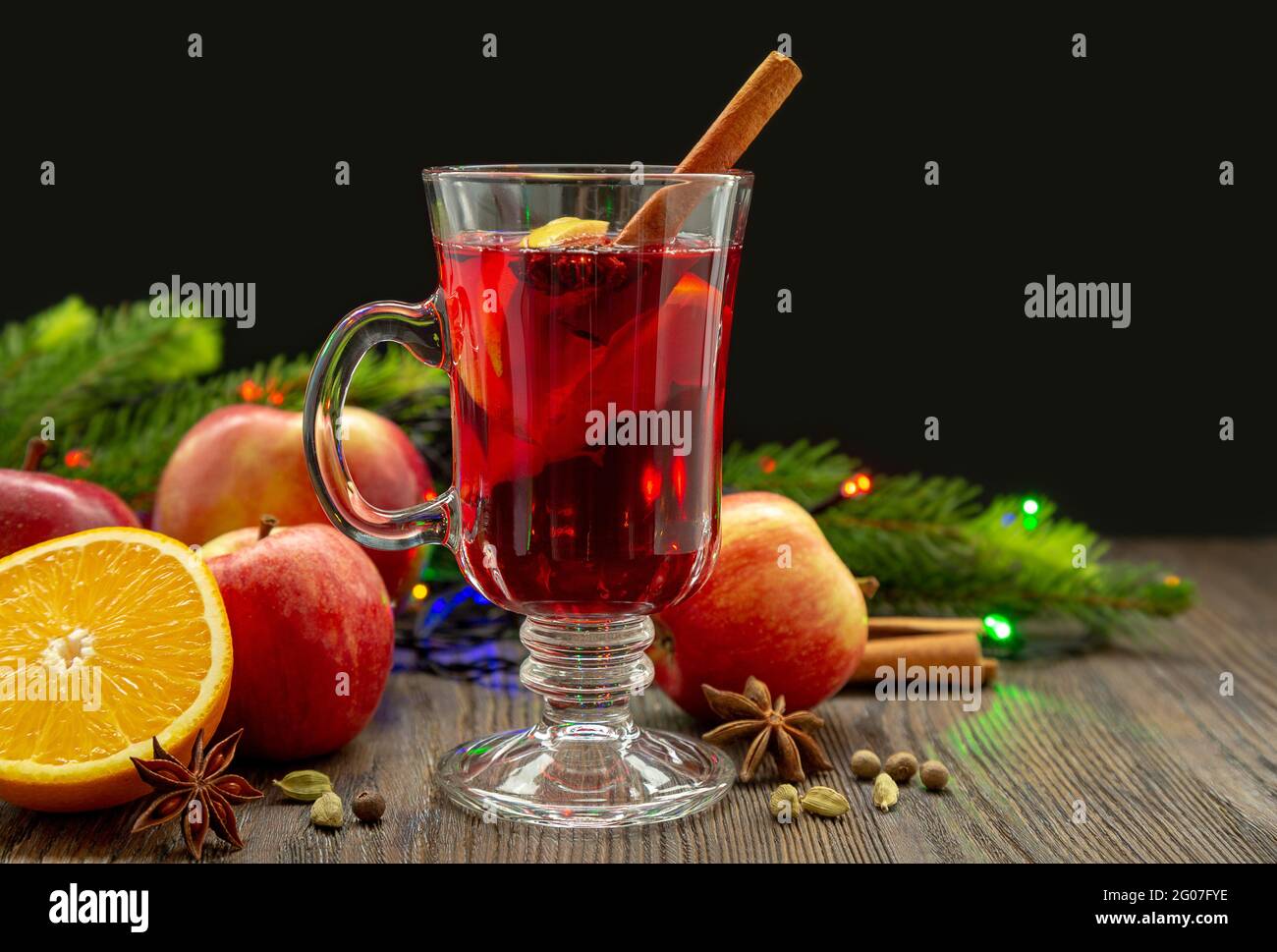 VIN brulé con spezie e frutta su un tavolo di legno su fondo nero. Tradizionale bevanda calda natalizia con vino rosso, mele, arance e cannella Foto Stock