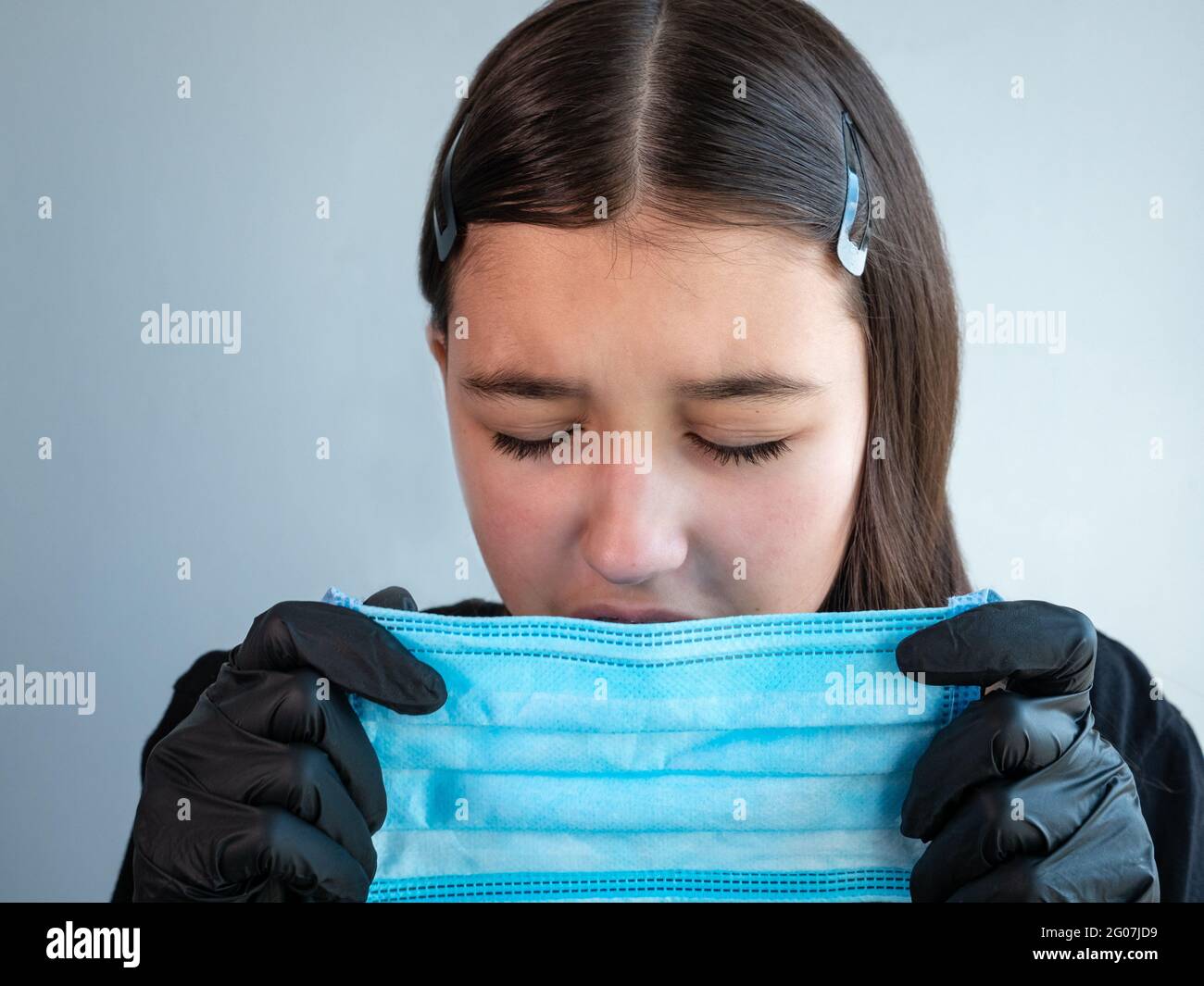 Una ragazza adolescente in nero guanti di lattice che tiene e starnutisce  in una maschera medica di protezione blu. Occhi chiusi. Concetto di  protezione antivirale Foto stock - Alamy