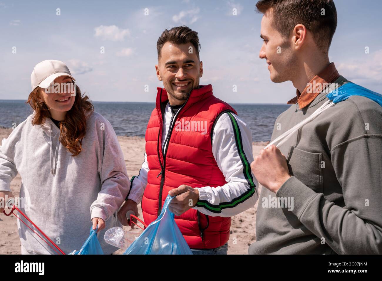 uomini felici e donna che raccolgono i rifiuti in sacchetti di spazzatura Foto Stock
