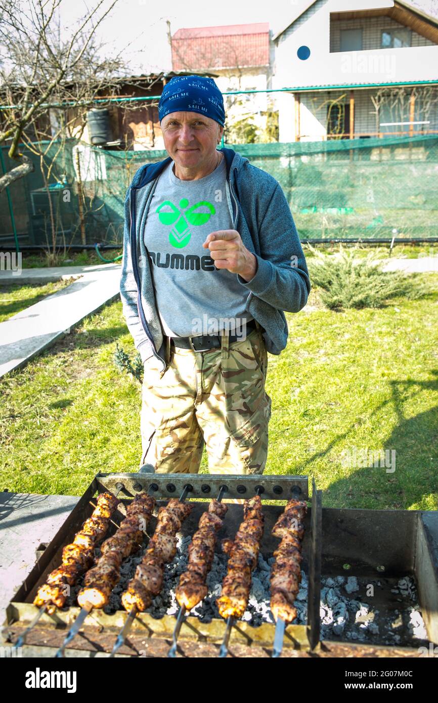 Picnic in natura. Un uomo sta grigliando i kebab marinati. Primo piano foto di kebab caucasici nel giardino cottage. Foto Stock
