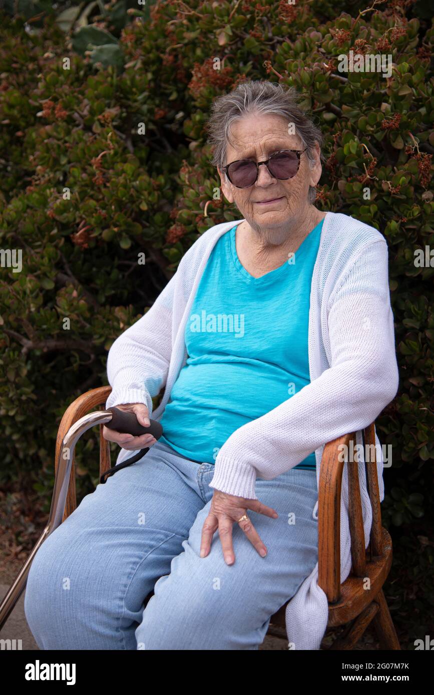 Una donna di 85 anni, indossando occhiali, seduta su una sedia. Foto Stock