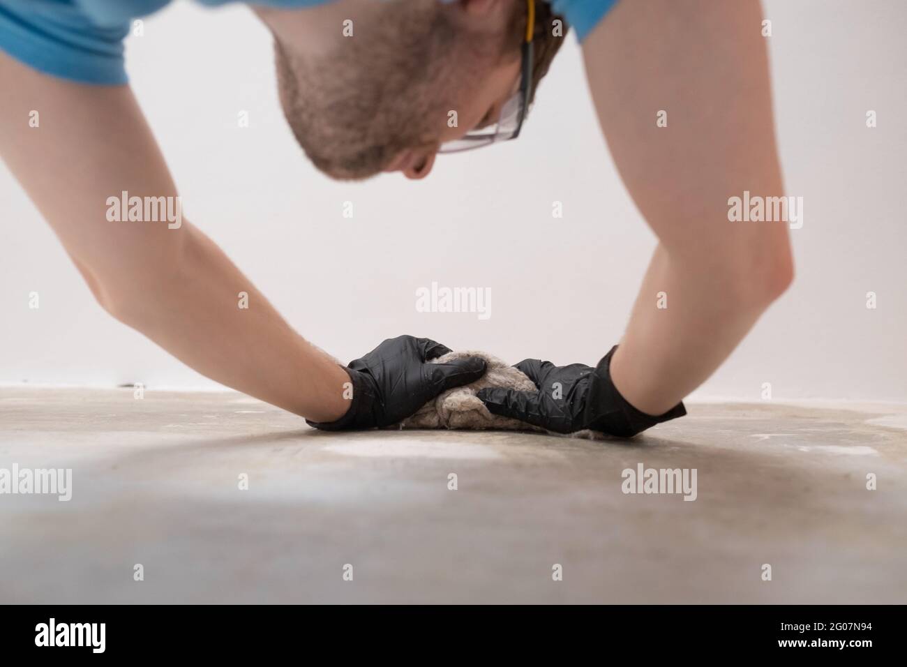 Uomo caucasico che lava le pareti dalla polvere usando il vecchio panno Foto Stock