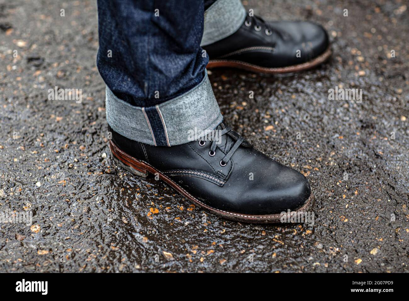 Primo piano di uomini in jeans e stivali in piedi su strada bagnata Foto  stock - Alamy