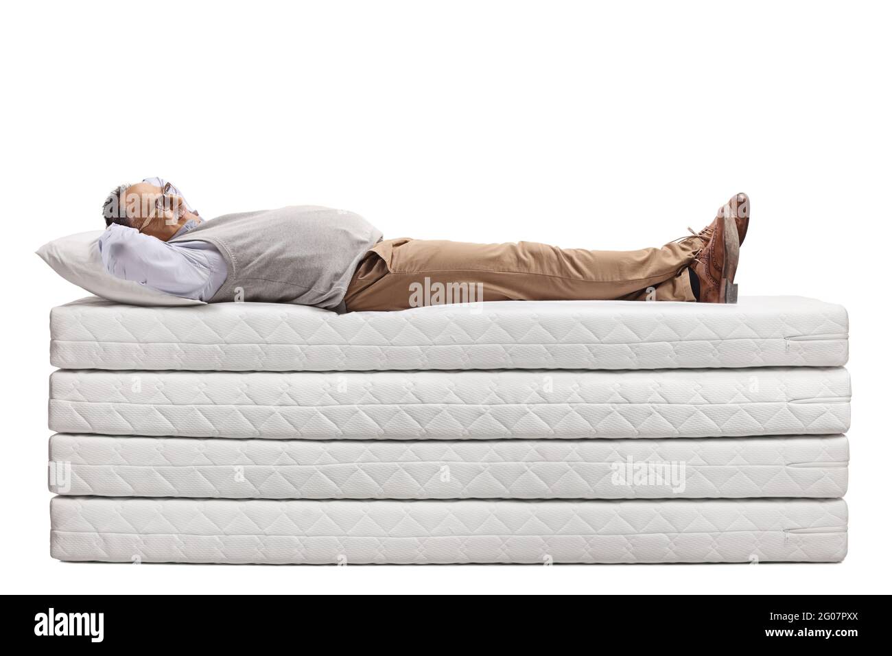 Uomo maturo sdraiato su un mucchio di materassi isolati su sfondo bianco Foto Stock