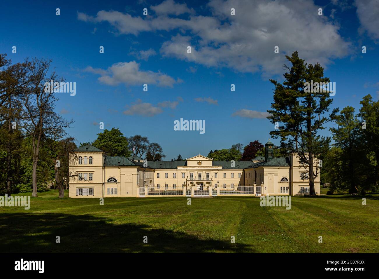 Lazne Kynzvart, Repubblica Ceca - Maggio 31 2021: Vista del castello, un edificio giallo in piedi in un parco. Erba verde in primo piano e gli alberi intorno Foto Stock