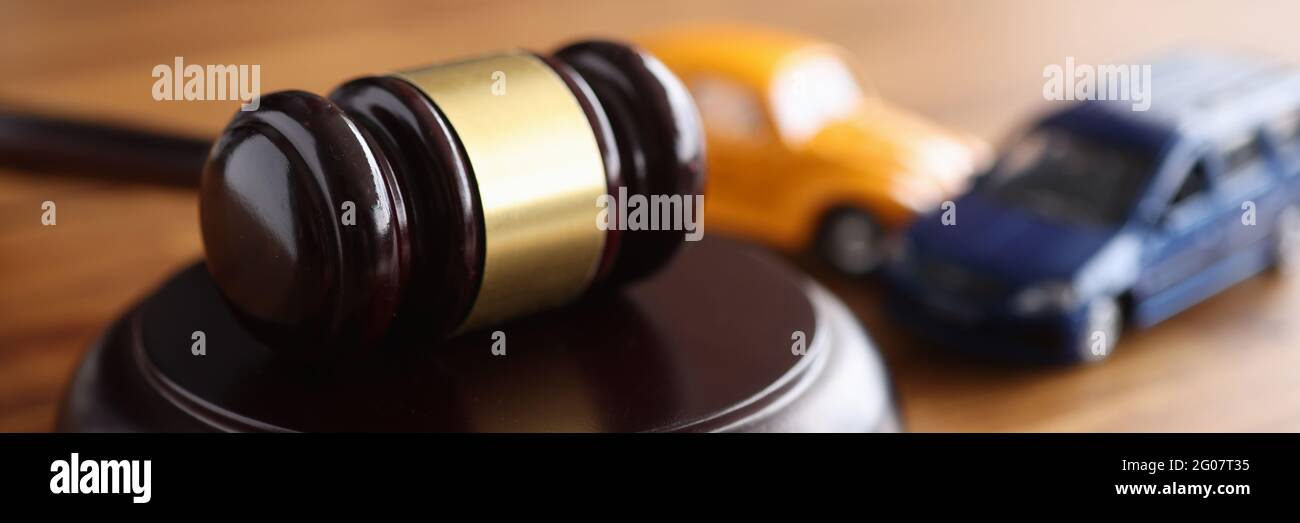 Giudica gavel di legno che giace sul tavolo vicino a macchine giocattolo closeup Foto Stock
