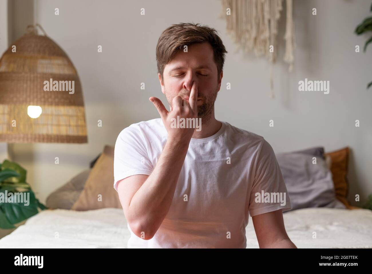 Uomo caucasico maturo che pratica yoga seduta, facendo Nostil alternato respirazione Foto Stock