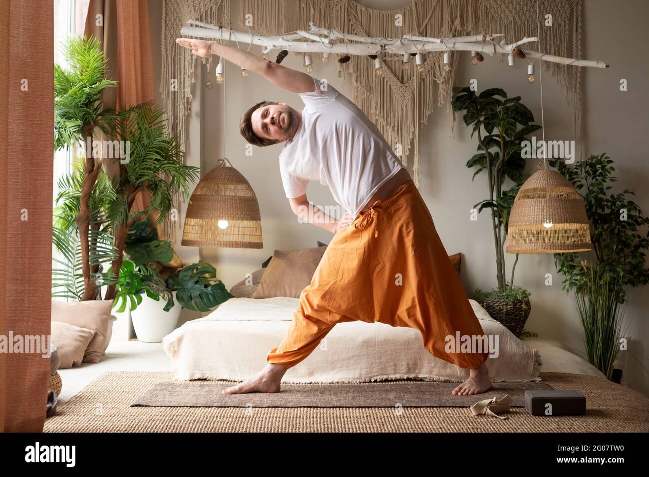 Uomo caucasico che pratica yoga trikonasana posa in soggiorno Foto Stock