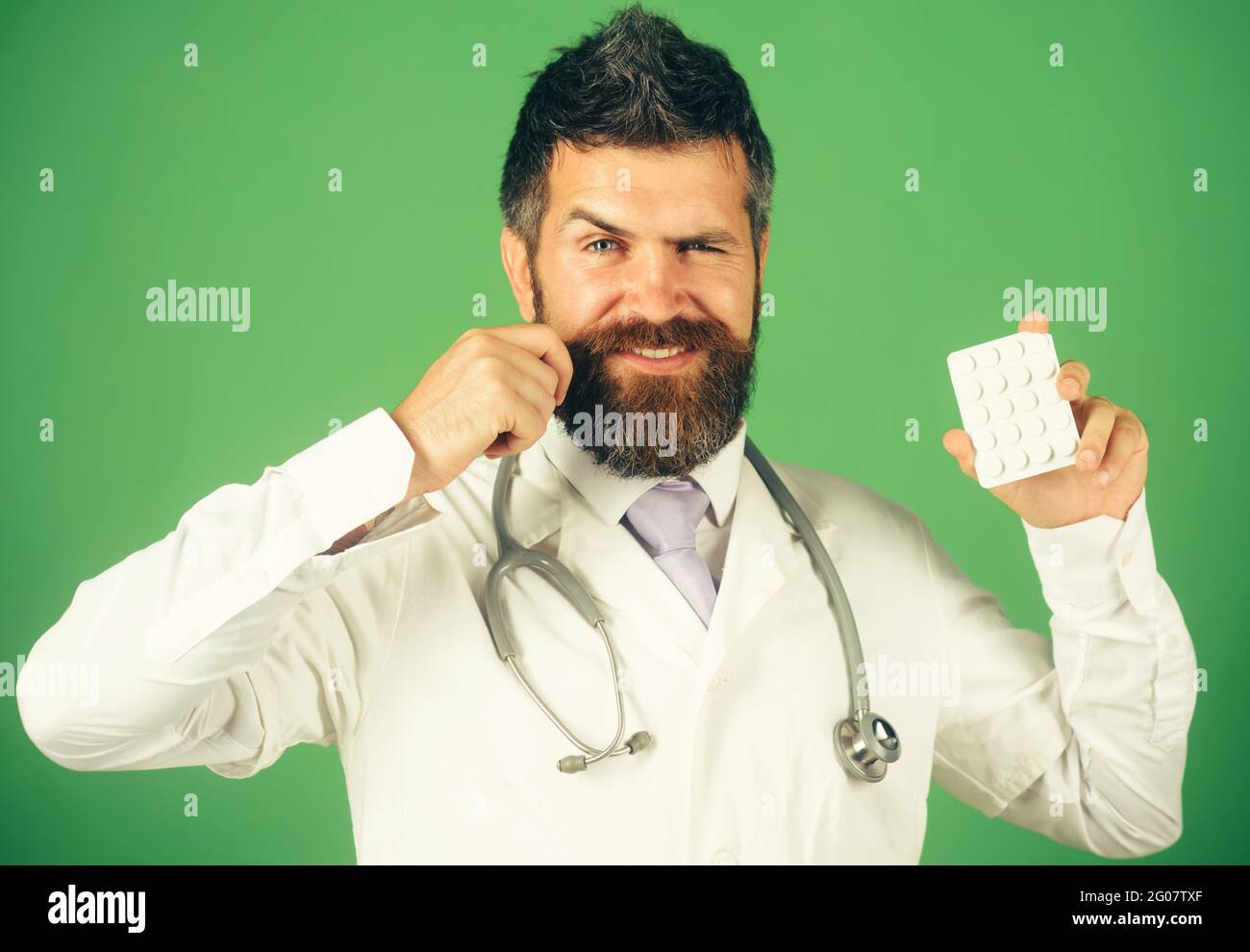 Trattamento e assistenza sanitaria. Sorridente medico o infermiere maschile con stetoscopio con pillole in mano. Foto Stock