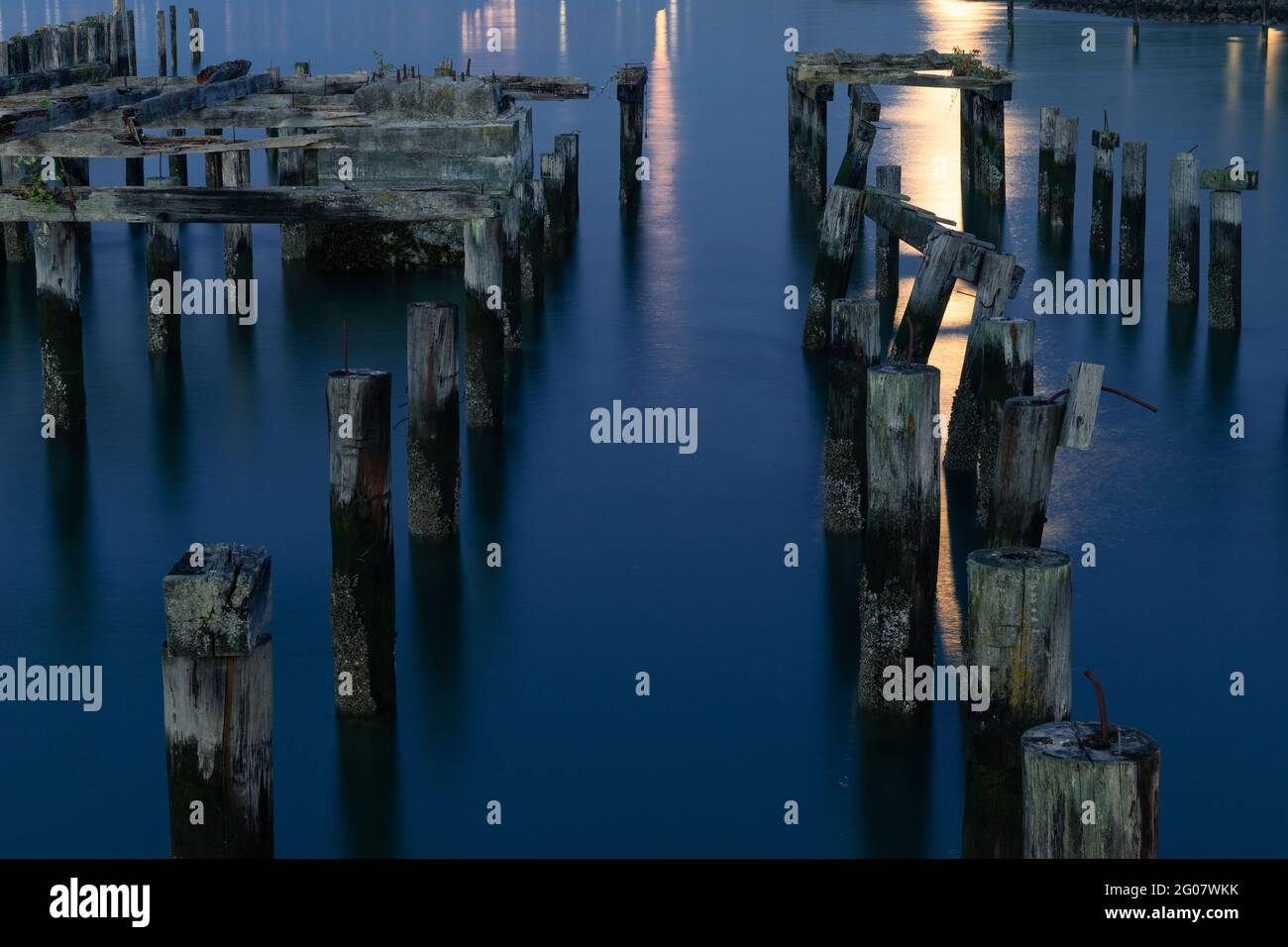Old Pier Pilings in acque tranquille e tranquille di notte Foto Stock
