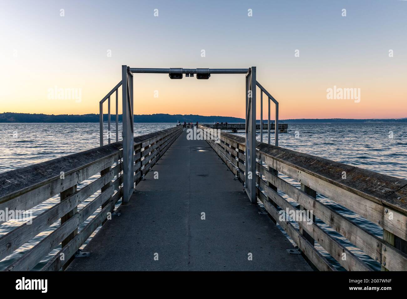 Tramonto con Long Pier che conduce in acqua Foto Stock