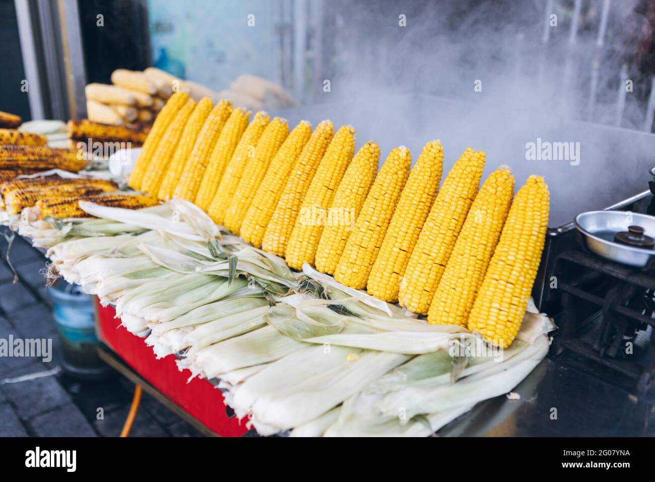 Pannocchie fresche di mais crude e fritte disposte su stalla di cena di  strada contro pentola di vapore in città in Turchia Foto stock - Alamy