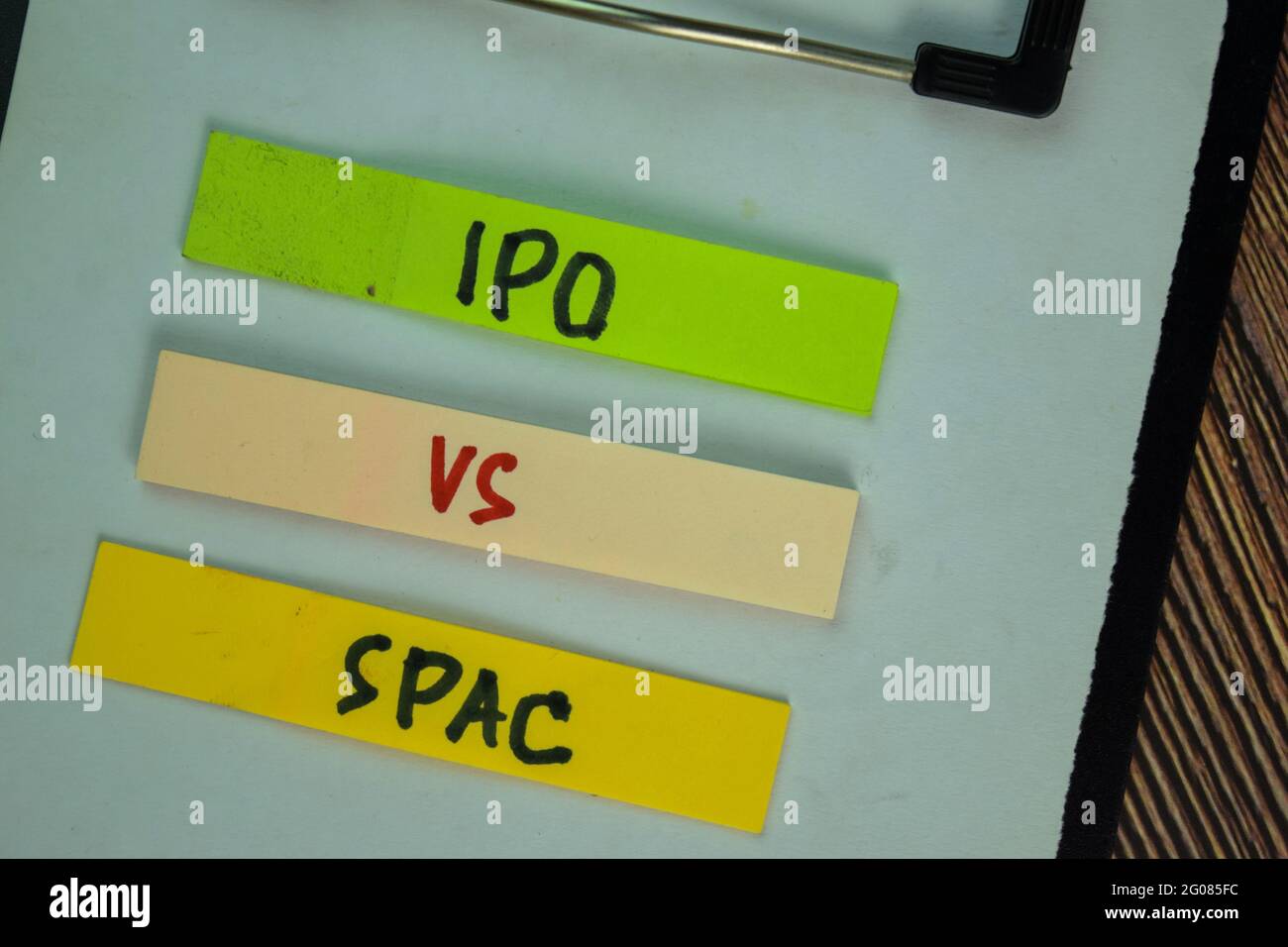 IPO Vs SPAC scrivono su note appiccicose isolate su tavola di legno. Foto Stock