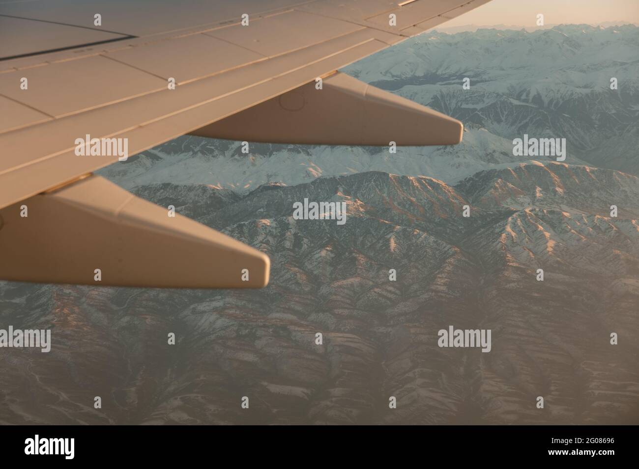 Vista panoramica sulle montagne innevate sotto l'ala dell'aereo Foto Stock