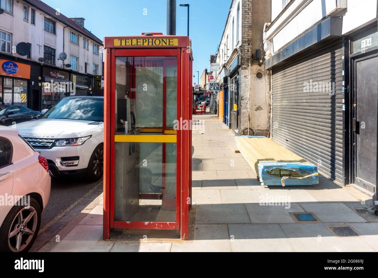 Una scatola telefonica rossa sul marciapiede sul lato di una strada a Hanwell, Londra, Regno Unito. Foto Stock