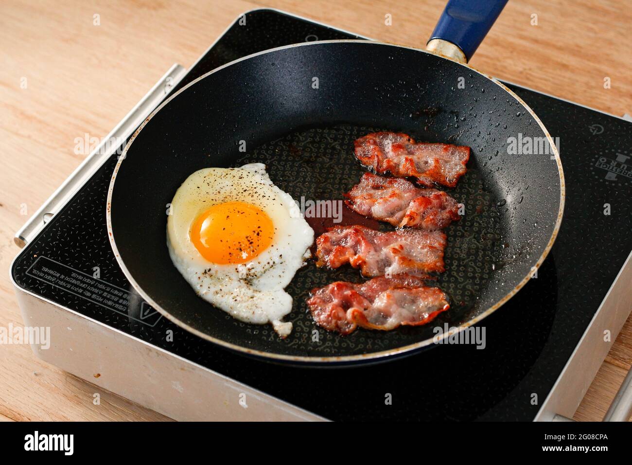 Gustosa colazione con uova fritte e pancetta in una padella Foto Stock