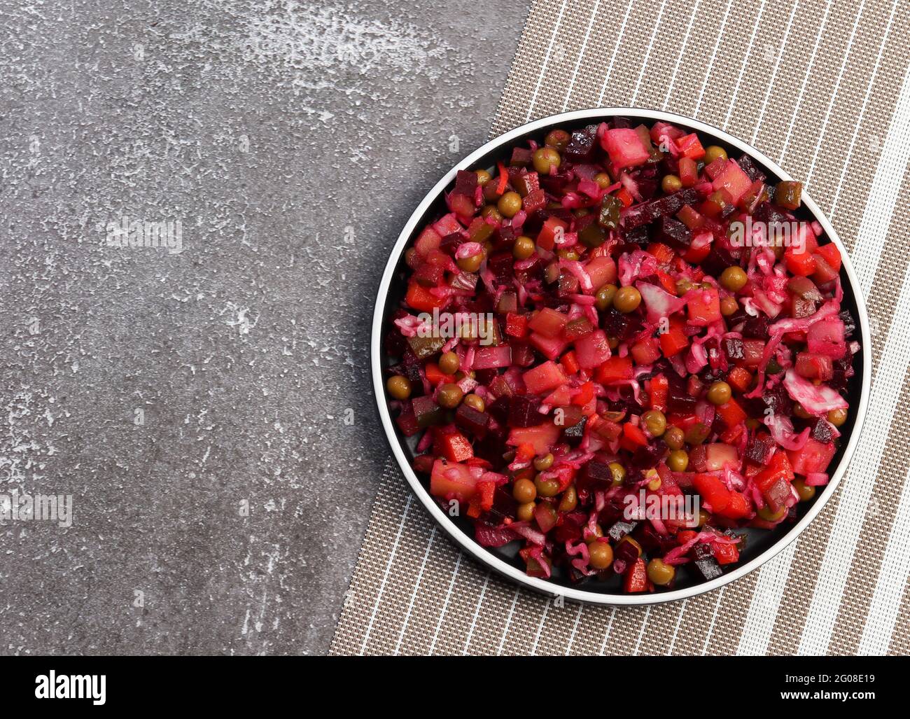 Vinaigrette tradizionale - insalata di barbabietole e verdure su un piatto rotondo su sfondo scuro. Vista dall'alto, disposizione piatta Foto Stock