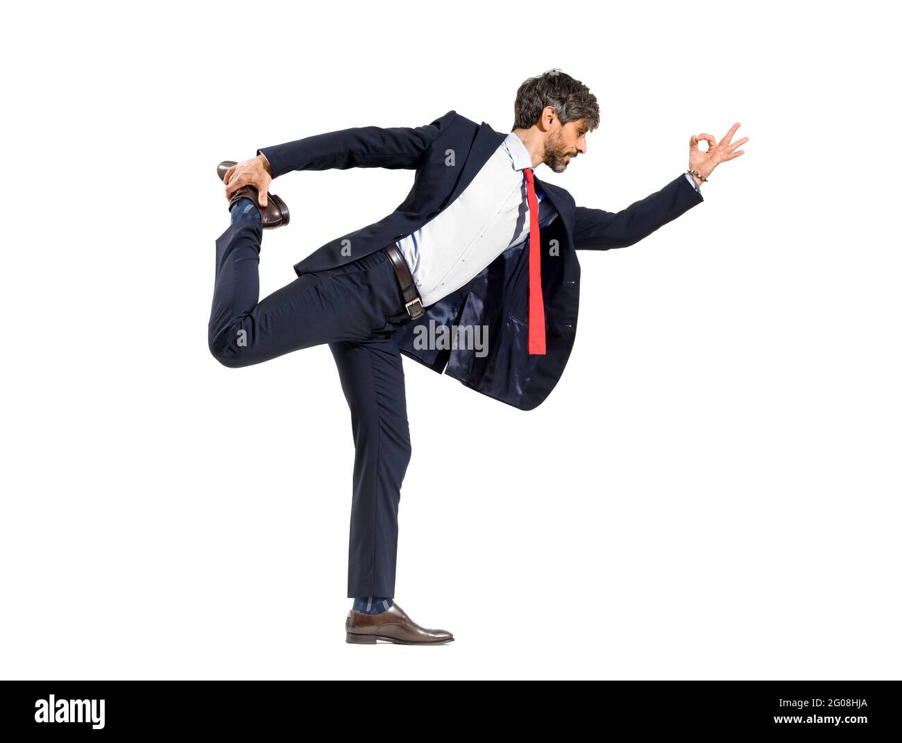 Un uomo d'affari intelligente di media età in una tuta facendo una ballerina di yoga posa l'equilibrio su una gamba in un tratto in avanti isolato su uno sfondo bianco dello studio Foto Stock