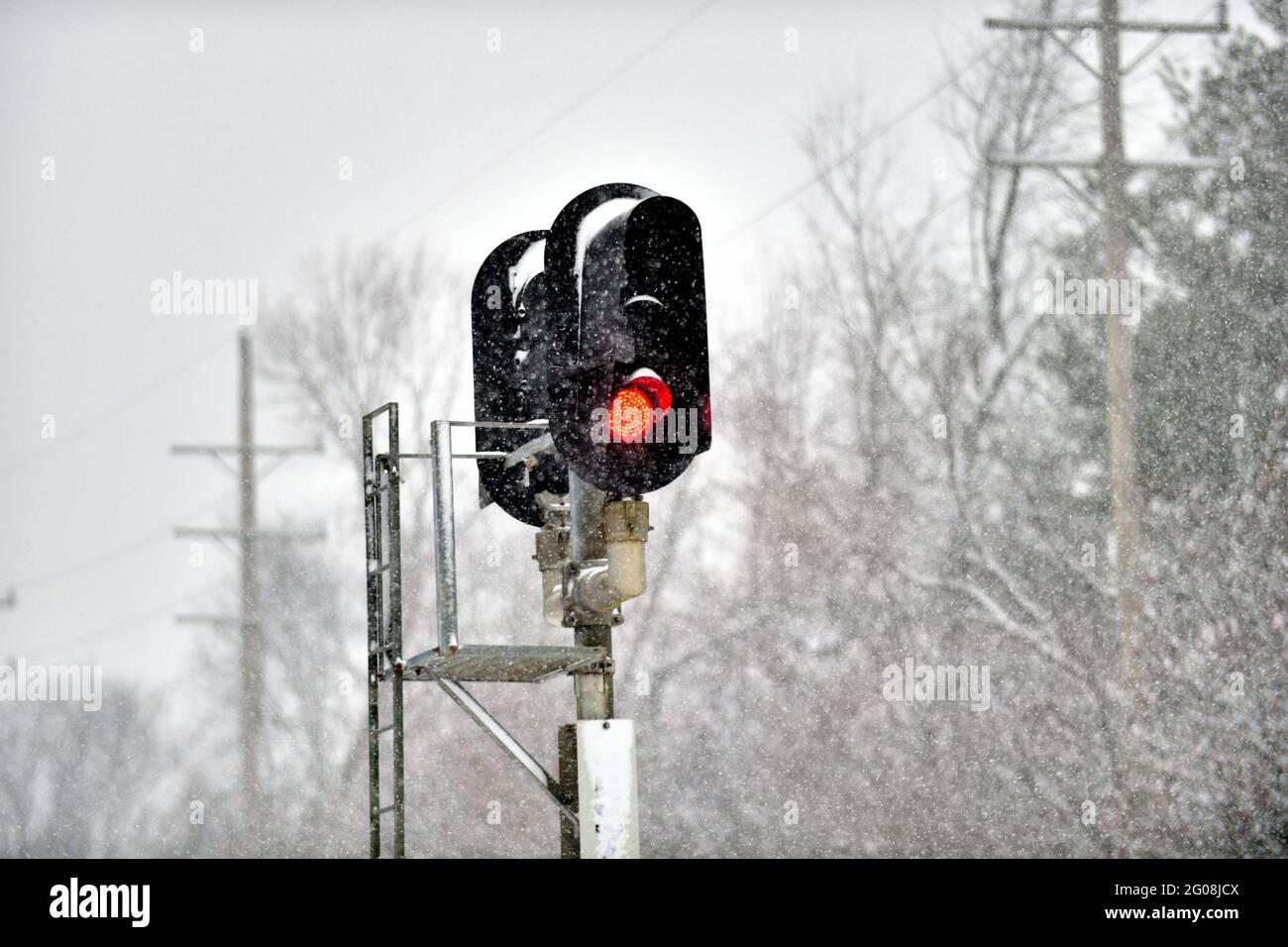Ginevra, Illinois, Stati Uniti. Un segnale ferroviario rosso si ferma durante una tempesta di neve invernale sulla linea principale Union Pacific Railroad nella periferia di Chicago. Foto Stock