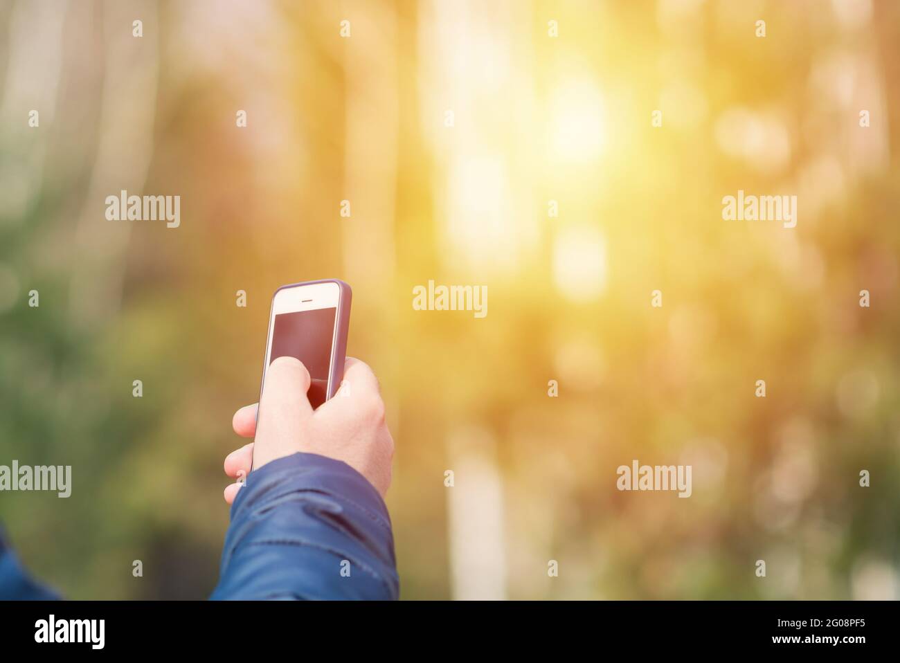 Un uomo con il suo smartphone cellulare alla ricerca del segnale di ricezione nella foresta primaverile soleggiata. Foto Stock
