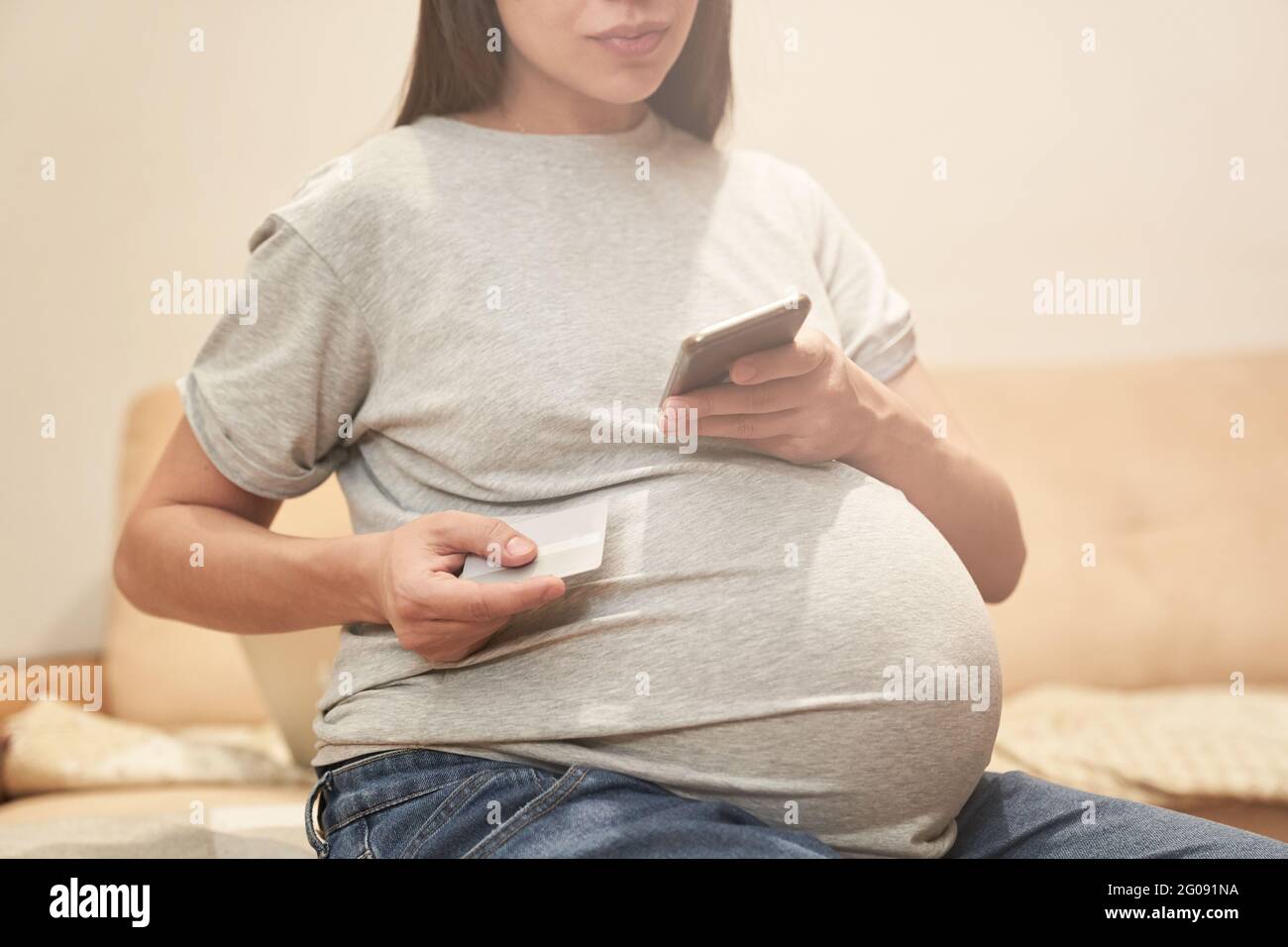 Donna incinta a casa con il telefono è seduto con il carrello di credito, concetto: Shopping online. Foto di alta qualità Foto Stock